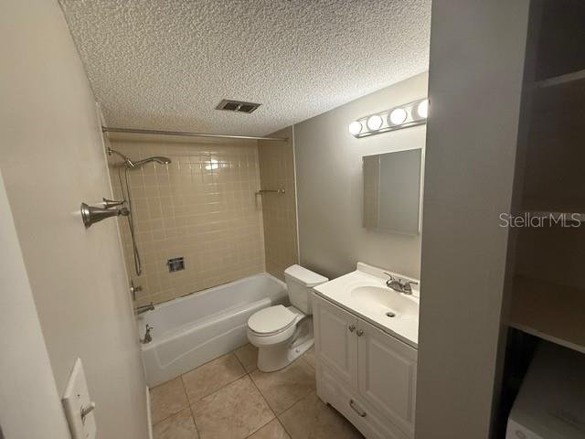 2763 Woodgate Ln Unit 111, Sarasota, FL 34231 - full bath with tile patterned floors, a textured ceiling, vanity, and shower / washtub combination
