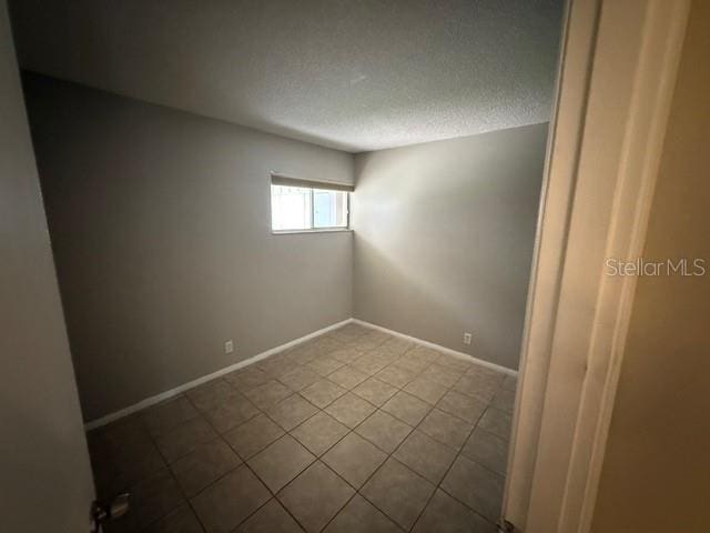 2763 Woodgate Ln Unit 111, Sarasota, FL 34231 - unfurnished room with tile patterned flooring and a textured ceiling