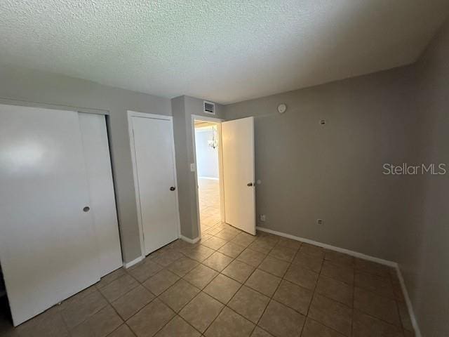 2763 Woodgate Ln Unit 111, Sarasota, FL 34231 - unfurnished bedroom featuring a textured ceiling and light tile patterned floors