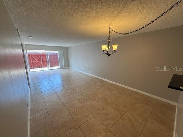 2763 Woodgate Ln Unit 111, Sarasota, FL 34231 - unfurnished room with a chandelier, a textured ceiling, and tile patterned flooring