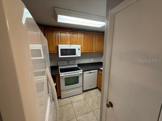 2763 Woodgate Ln Unit 111, Sarasota, FL 34231 - kitchen with white appliances, light tile patterned flooring, dark countertops, and brown cabinets