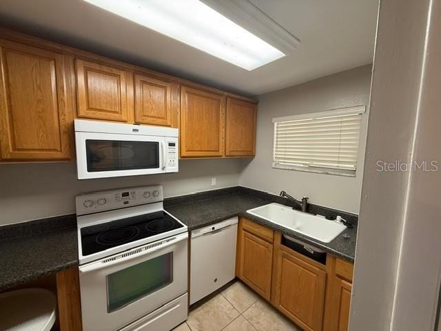 2763 Woodgate Ln Unit 111, Sarasota, FL 34231 - kitchen with white appliances, dark countertops, light tile patterned floors, and brown cabinetry