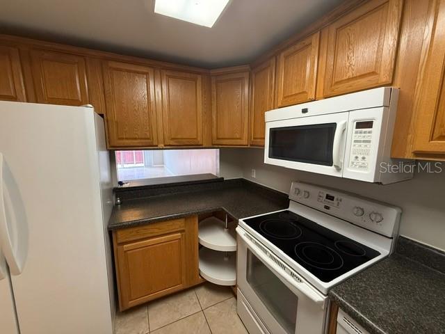 2763 Woodgate Ln Unit 111, Sarasota, FL 34231 - kitchen featuring white appliances, brown cabinets, and dark countertops