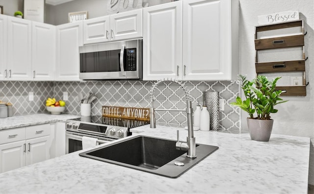 2419 29th Ave E, Palmetto, FL 34221 - kitchen featuring appliances with stainless steel finishes, tasteful backsplash, white cabinetry, and light stone counters