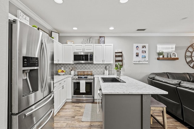 2419 29th Ave E, Palmetto, FL 34221 - kitchen featuring appliances with stainless steel finishes, open floor plan, a kitchen bar, ornamental molding, and white cabinetry