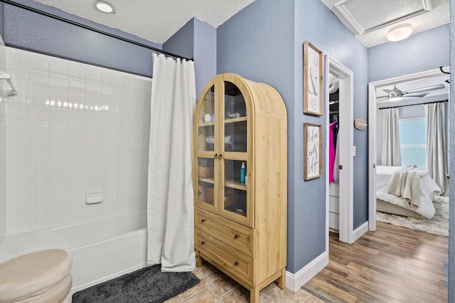 2419 29th Ave E, Palmetto, FL 34221 - bathroom featuring a textured wall, shower / bathtub combination with curtain, and wood finished floors