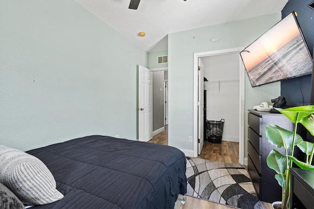 2419 29th Ave E, Palmetto, FL 34221 - bedroom featuring wood finished floors, a walk in closet, vaulted ceiling, and ceiling fan