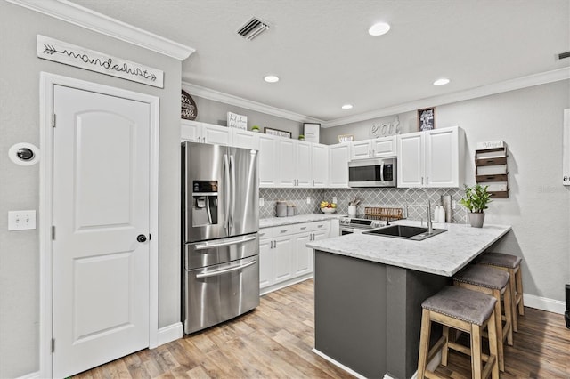 2419 29th Ave E, Palmetto, FL 34221 - kitchen with stainless steel appliances, a peninsula, crown molding, a kitchen bar, and white cabinets
