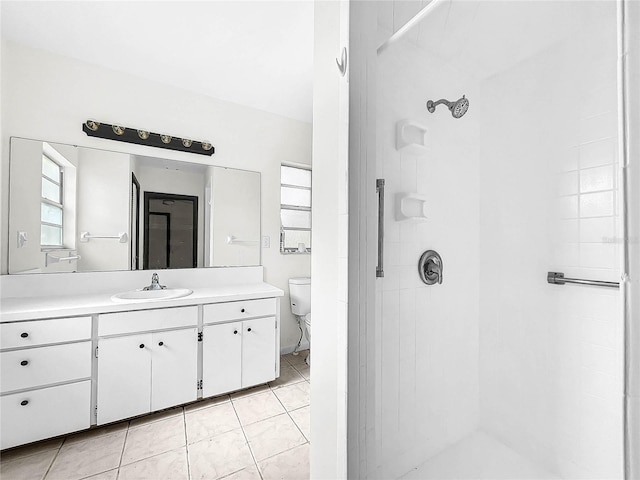 bathroom featuring vanity, toilet, a tile shower, and tile patterned flooring