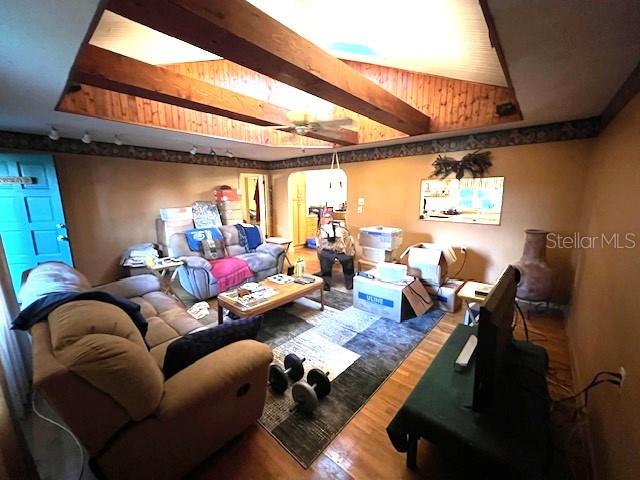 cinema featuring dark hardwood / wood-style floors, beam ceiling, and ceiling fan