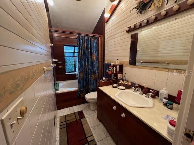 full bathroom with tile walls, shower / bath combination with curtain, toilet, and vanity with extensive cabinet space