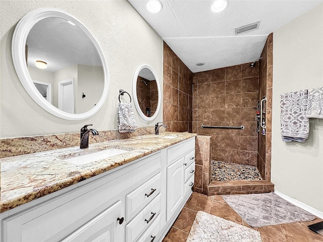 bathroom with tile flooring, tiled shower, oversized vanity, and double sink