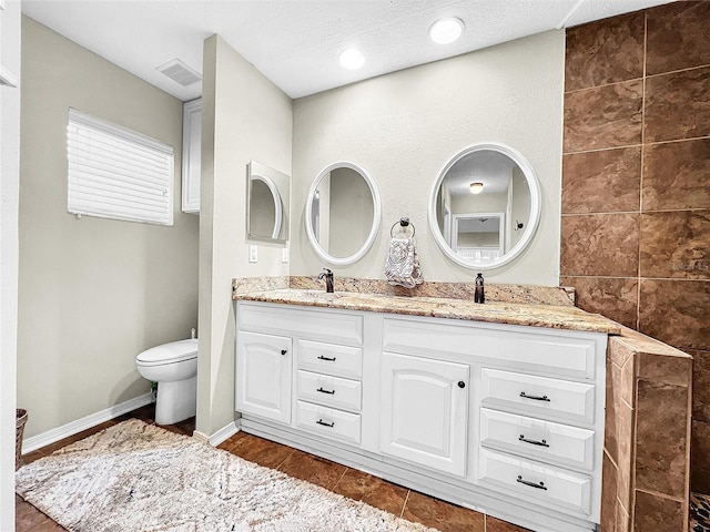 bathroom featuring tile floors, tile walls, large vanity, double sink, and toilet