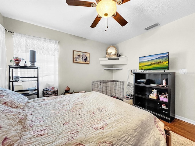 bedroom featuring hardwood / wood-style flooring, ceiling fan, and a textured ceiling