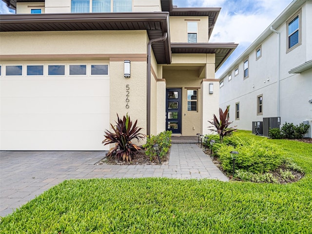 entrance to property with a yard, a garage, and central AC