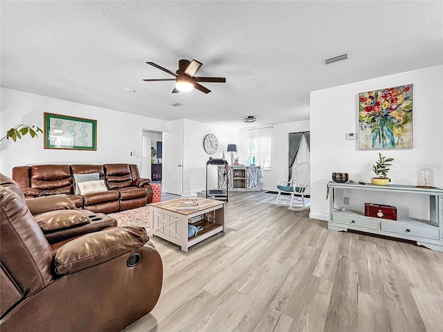 living room featuring a textured ceiling, light hardwood / wood-style floors, and ceiling fan