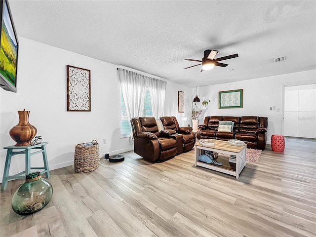 living room with light wood-type flooring, a textured ceiling, and ceiling fan