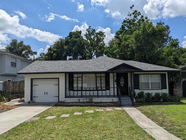 single story home featuring a garage, a front lawn, and covered porch