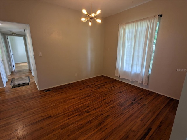 unfurnished room featuring a notable chandelier and dark wood-type flooring