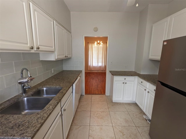 kitchen featuring sink, white cabinetry, light tile patterned floors, stainless steel refrigerator, and backsplash