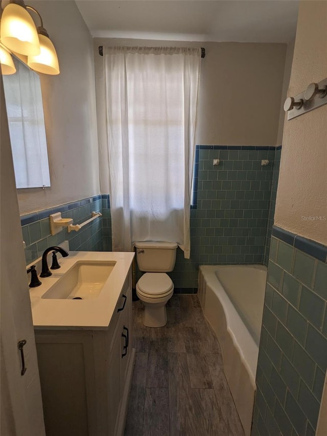 bathroom with tile walls, a healthy amount of sunlight, vanity, and toilet