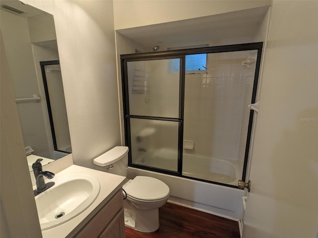 full bathroom featuring vanity, hardwood / wood-style floors, enclosed tub / shower combo, and toilet