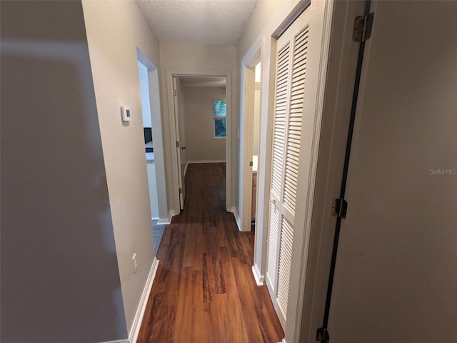 hall with dark wood-type flooring and a textured ceiling