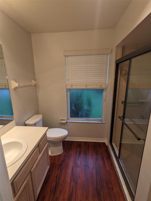 bathroom featuring hardwood / wood-style flooring, vanity, a shower with door, and toilet