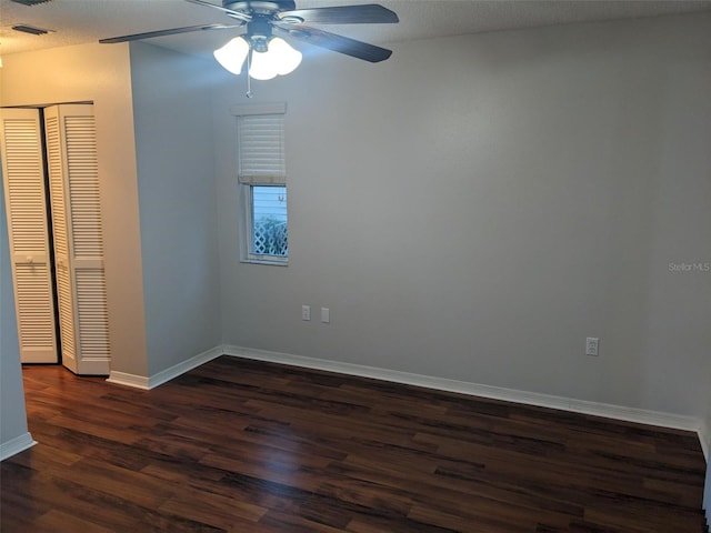 spare room featuring dark wood-type flooring, ceiling fan, and a textured ceiling