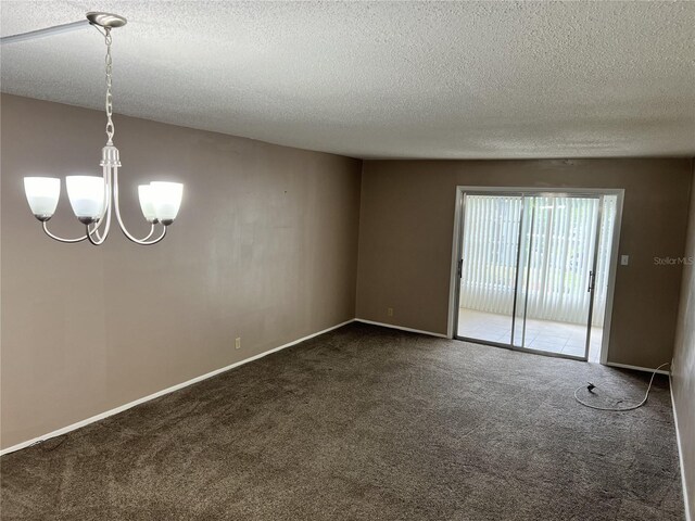 unfurnished room featuring a notable chandelier, dark colored carpet, and a textured ceiling