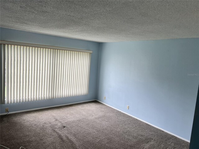 carpeted empty room featuring a textured ceiling