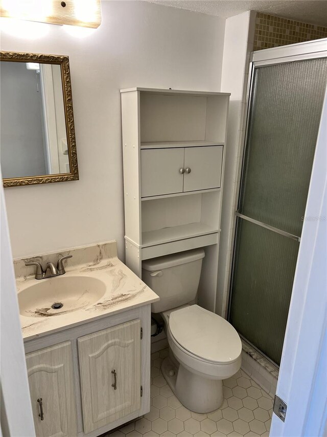 bathroom with tile patterned floors, toilet, vanity, and an enclosed shower