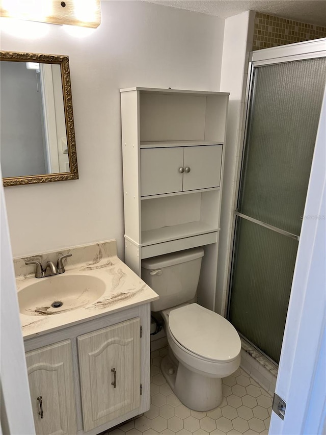 bathroom with toilet, a shower with door, and vanity