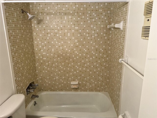 bathroom featuring tiled shower / bath combo and toilet