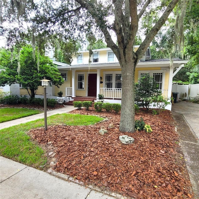 view of front of home featuring covered porch and fence