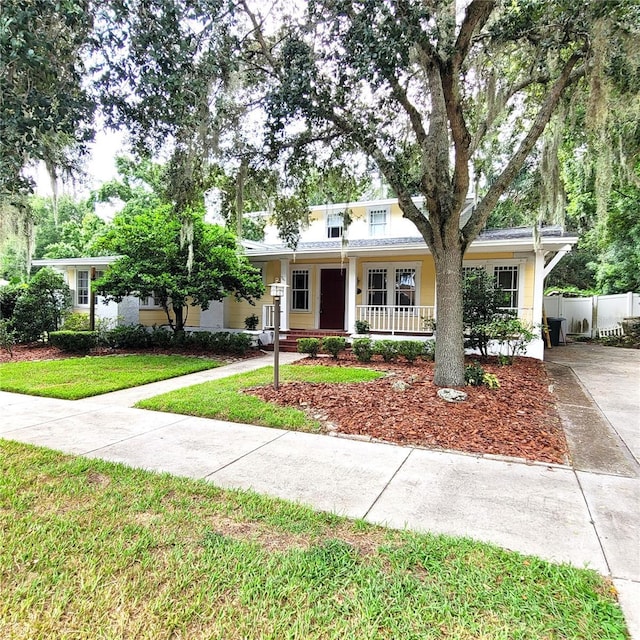 view of front of property featuring a porch, a front yard, concrete driveway, and fence