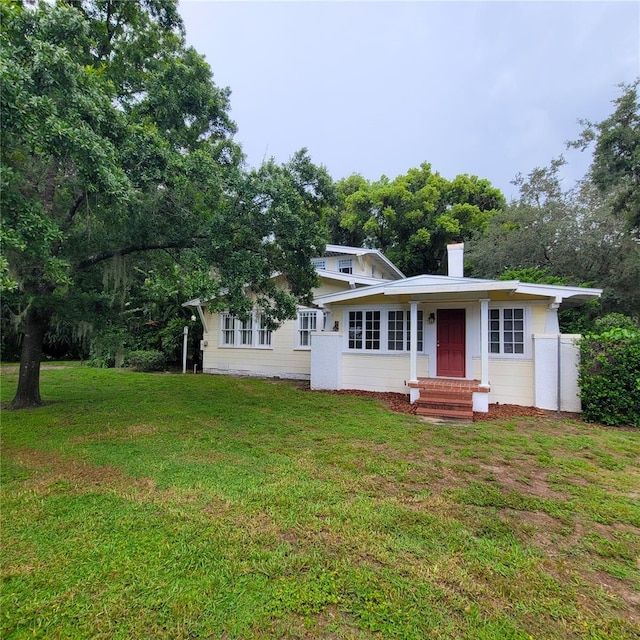 ranch-style home with entry steps, a chimney, and a front yard