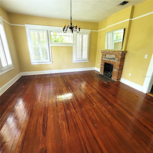 unfurnished living room featuring hardwood / wood-style flooring, a brick fireplace, visible vents, and baseboards