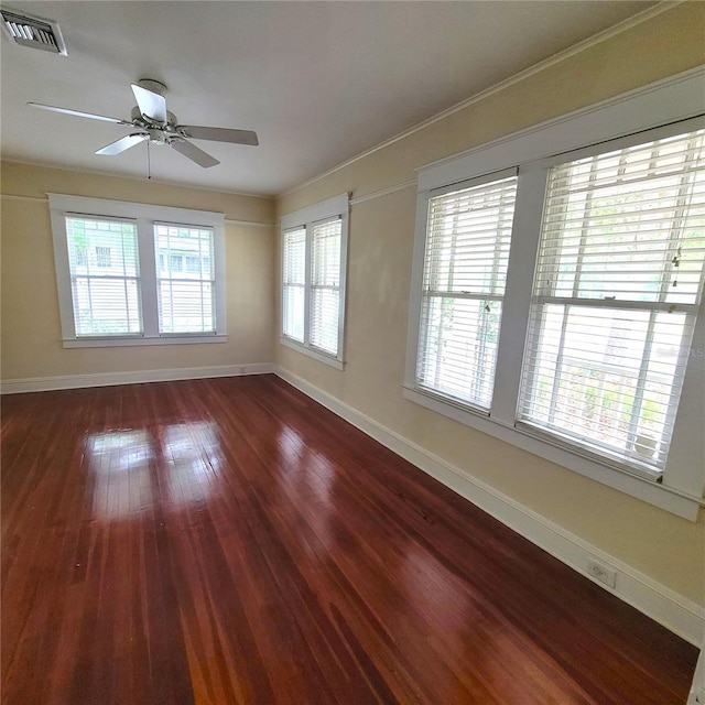 unfurnished room with a ceiling fan, visible vents, baseboards, hardwood / wood-style floors, and crown molding