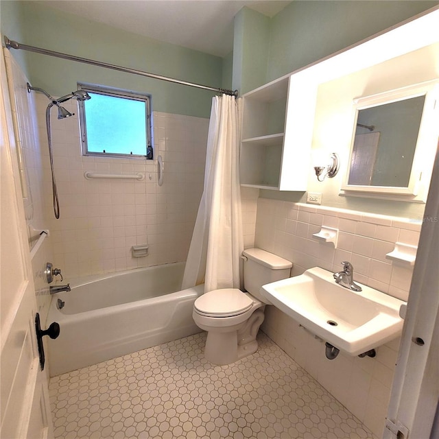 bathroom with toilet, shower / bath combo, a sink, and tile walls