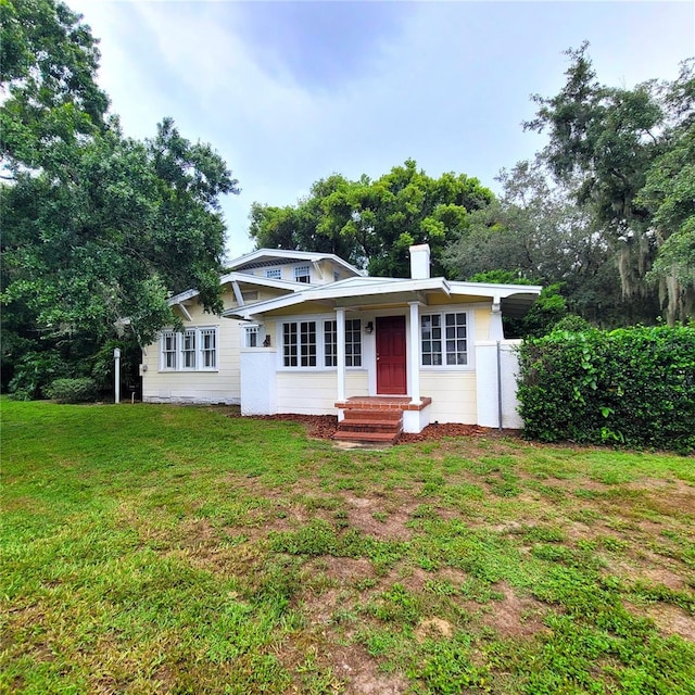 view of front of house with entry steps, a chimney, and a front yard