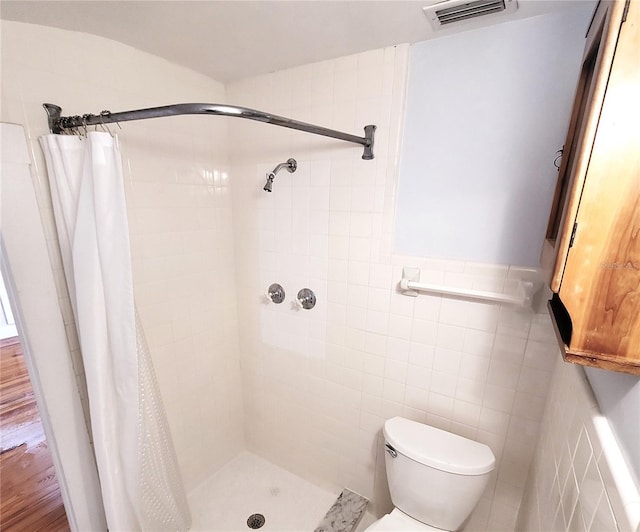 full bath with a stall shower, visible vents, tile walls, and toilet