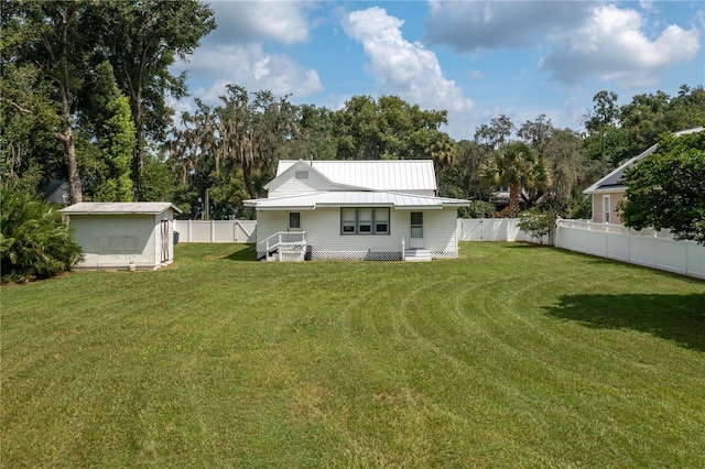 rear view of house featuring a yard and a storage shed