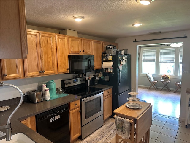 kitchen featuring a textured ceiling, light tile patterned floors, sink, and black appliances