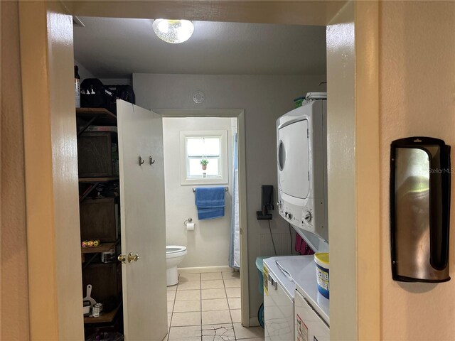 laundry room featuring light tile patterned floors and stacked washer and clothes dryer