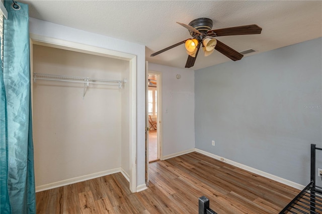 unfurnished bedroom with a textured ceiling, ceiling fan, a closet, and light hardwood / wood-style floors