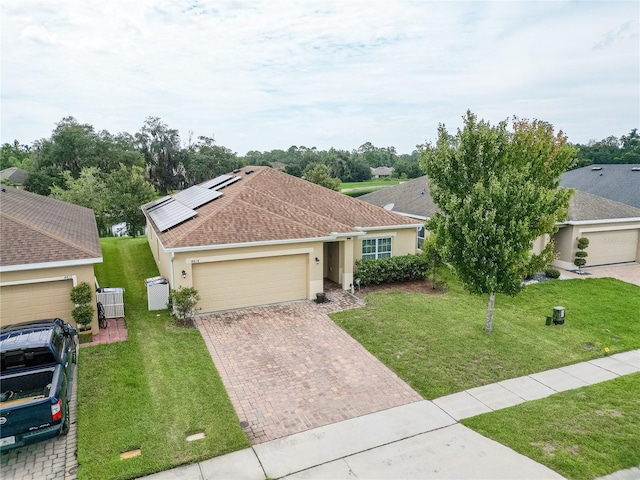 single story home with a front yard, solar panels, and a garage