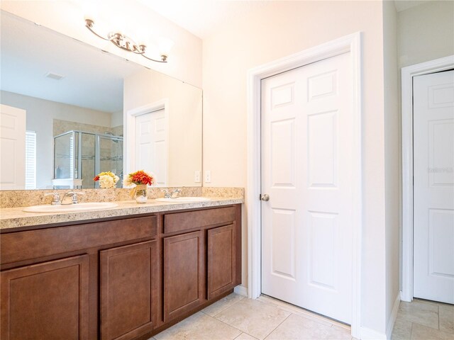 bathroom with tile patterned flooring, a shower with door, and dual vanity