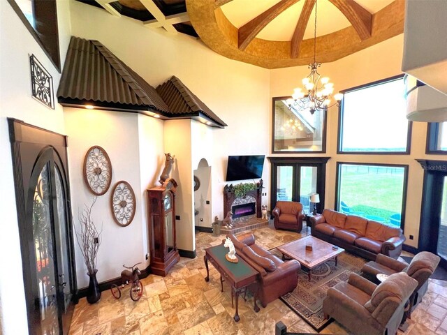 living room with a high ceiling, tile patterned flooring, an inviting chandelier, and coffered ceiling