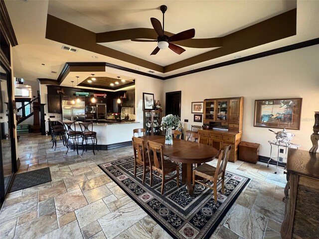 dining room with ceiling fan, tile patterned floors, a tray ceiling, and ornamental molding